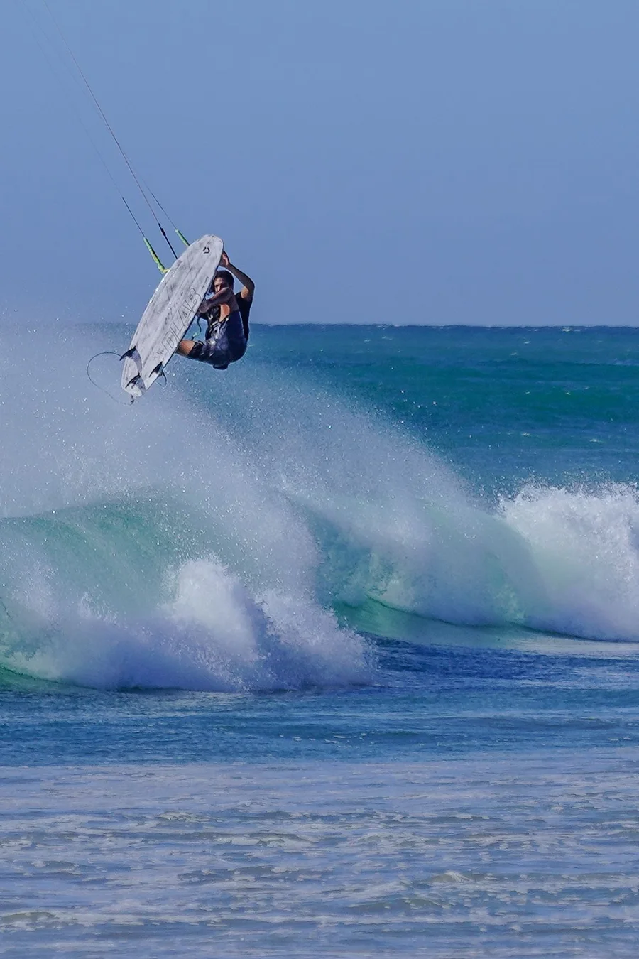 Un kitesurfeur en surf directionnel réalise un virage au-dessus d’une vague